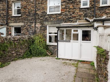An outdoor area with a stone wall and cottage entrance at Waterhead Cottage in Ambleside