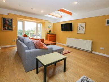 A living room with a sofa, table, and television at Inglewood Bach in Conwy