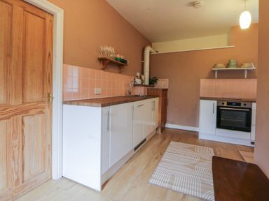 A kitchen with cabinets and an oven at Inglewood Bach in Conwy