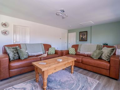 A living room with brown sofas and a wooden table at Star Carr Lakes