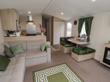 A living room with a sofa, dining table, and kitchen appliances at Homeslea 33 Millennium Gardens in Morpeth