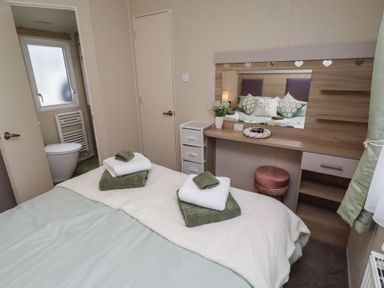 A bedroom with a bed and a dressing table at Homeslea 33 Millennium Gardens, Morpeth