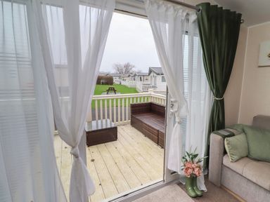 A living room with a sliding door leading to a deck at Homeslea 33 Millennium Gardens Morpeth