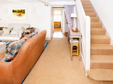 A living room with a sofa and staircase at Gardeners Cottage in Chipping Norton
