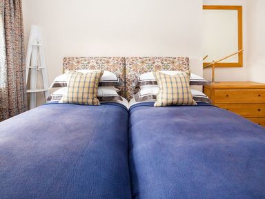 A bedroom with two beds and decorative headboard at Gardeners Cottage in Chipping Norton