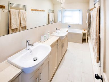 A bathroom with sinks and a bathtub at Gardeners Cottage in Chipping Norton