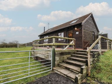 A cabin with steps leading to a fenced outdoor area at The Barn on The Lagoon Droitwich