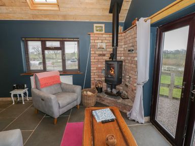 A living room with a stove and a chair at The Barn on The Lagoon in Droitwich