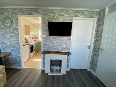 A living room with a television and fireplace at Chalet 58 in California, Norfolk
