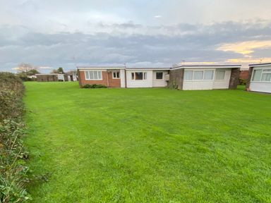 An outdoor area with green grass and three buildings at Chalet 333 California, Norfolk