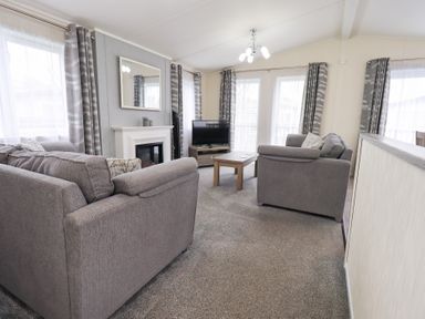 A living room with sofas and a television at Lily's Lodge in Morecambe