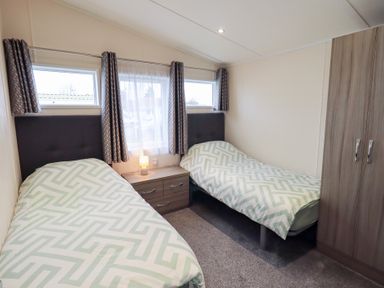 A bedroom with two beds and a wardrobe at Lily's Lodge in Morecambe