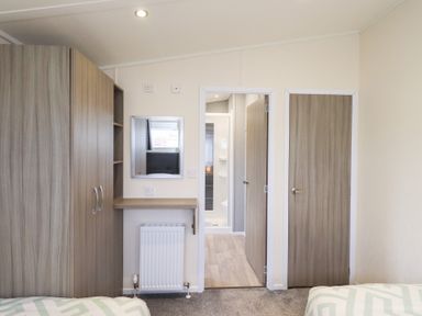 A bedroom with a wardrobe and a mirror at Lily's Lodge Morecambe