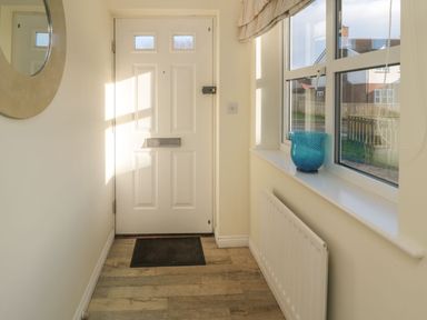 A hallway with a door and windows at Sandy Cove, Chathill
