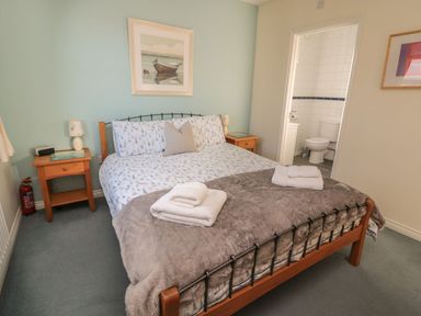 A bedroom with a bed and an adjoining bathroom at Sandy Cove in Chathill