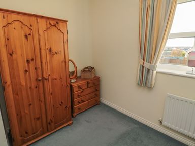 A bedroom with wardrobe and dresser at Sandy Cove in Chathill