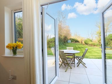 A dining area with a table and chairs overlooking a garden at The Pebble in Dorchester