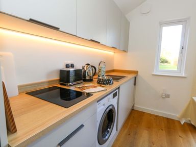 A kitchen with a countertop, stove, and washing machine at The Pebble in Dorchester