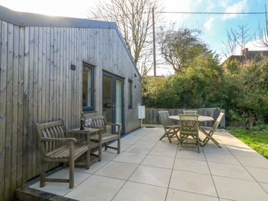 A garden patio with wooden furniture at The Pebble in Dorchester