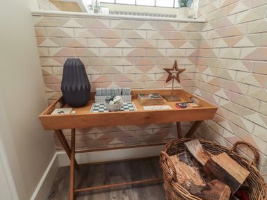 An entryway with a table, vase, and firewood at Summerset Lodge in Bamburgh