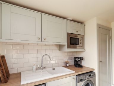 A kitchen with cabinets, sink, microwave, coffee machine, and washing machine at Summerset Lodge, Bamburgh