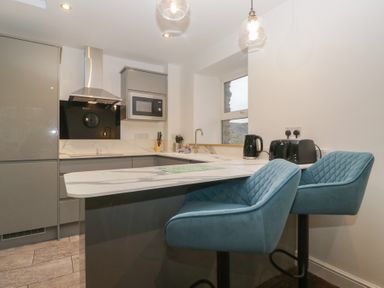 A kitchen with bar stools and appliances at 6 Hallin Fell in Penrith