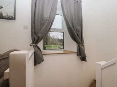 A staircase landing with a window and curtains at 6 Hallin Fell in Penrith