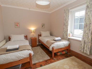 A bedroom with two beds and a window at 1 Alpha Cottages in Tenby
