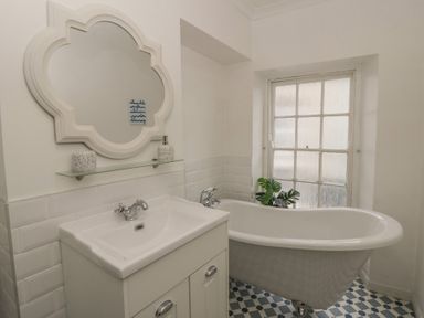 A bathroom featuring a bathtub, sink, and mirror at 1 Alpha Cottages Tenby