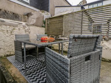An outdoor seating area with a table and chairs at 1 Alpha Cottages in Tenby