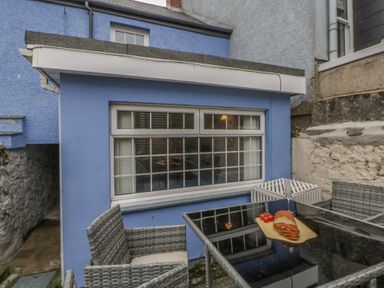 An outdoor seating area with a table and chairs at 1 Alpha Cottages Tenby