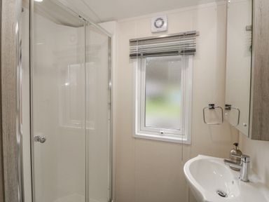 A bathroom with a shower, sink, and mirror at The Ridgeway New Quay