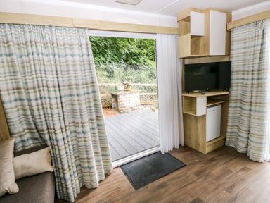 A living room with a sliding door and television at The Pod in Ferryside