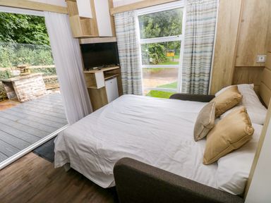 A bedroom with a bed and television at The Pod in Ferryside