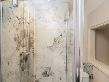 A shower with marble walls and a toilet in Paddock View Stow-On-The-Wold