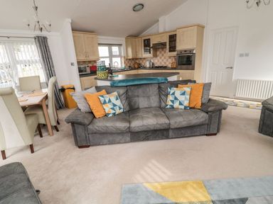 A living room with a sofa and dining area at Nevaeh Lodge Longframlington