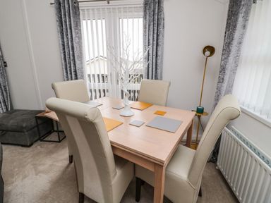 A dining room with a table and chairs at Nevaeh Lodge Longframlington