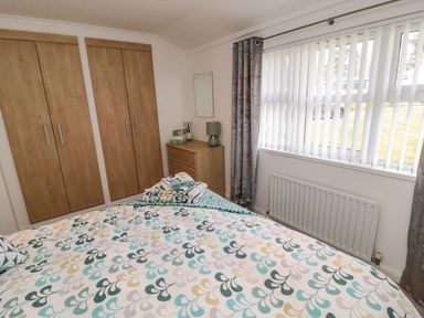 A bedroom with a bed and wardrobe at Nevaeh Lodge Longframlington