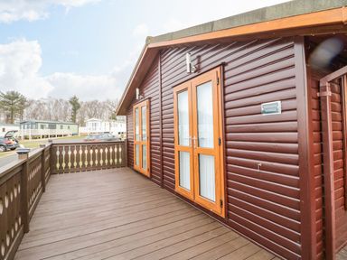 An outdoor area with decking and double doors at Nevaeh Lodge Longframlington