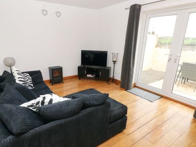A living room with a sofa and television at Red Kite Cottage in Haverfordwest