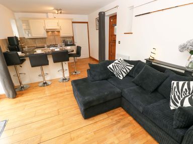 A living room with a sofa and bar stools at Red Kite Cottage in Haverfordwest