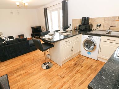A kitchen with a washing machine and sofa at Red Kite Cottage in Haverfordwest
