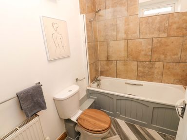 A bathroom with bathtub, toilet and wall art at Red Kite Cottage in Haverfordwest
