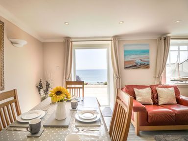 A dining room with a table and chairs overlooking the sea at Ocean Wave in Greenhill
