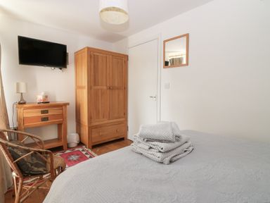 A bedroom with a bed, television, and wooden wardrobe at Mill Wharf in Berwick-upon-Tweed