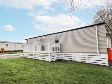 A mobile home with a deck in an outdoor area at Hadrian's Rest in Wigton