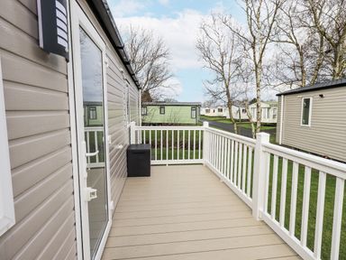 An outdoor decking area with a railing and storage box at Hadrian's Rest in Wigton