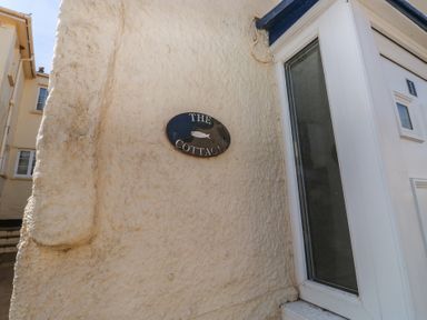 A nameplate on the wall next to a door at The Cottage in Budleigh Salterton