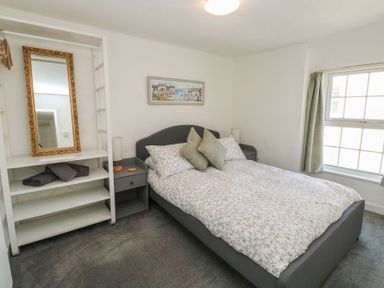 A bedroom with a bed and shelves at The Cottage in Budleigh Salterton