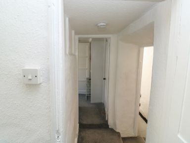 A hallway with a light switch and doors at The Cottage in Budleigh Salterton